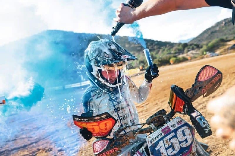 Emy Ochalek arrosée à l'arrivée, sur sa moto numéro 159, devant un fumigène bleu