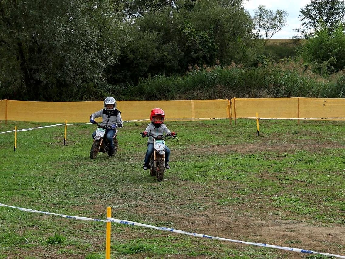 Deux enfants font leurs premiers tours sur un parcours balisé dans l'herbe